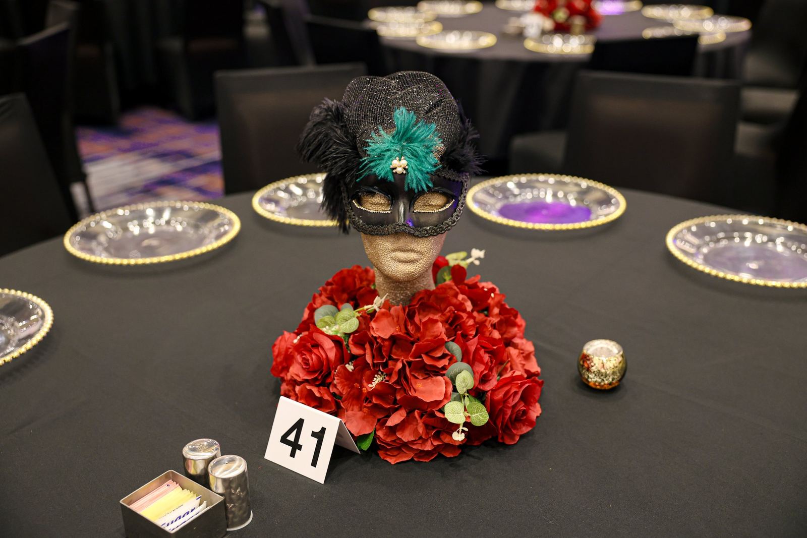 A gala table set with a masquerade mask and red roses at the CARE 2025 Gala