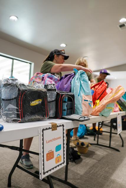 Volunteers setting out backpacks and supplies on a table