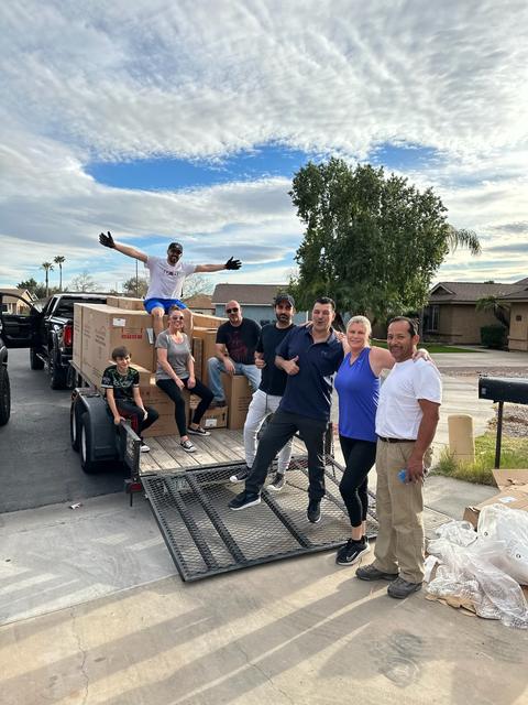 CARE volunteers standing on a trailer loaded with supplies under a big blue sky