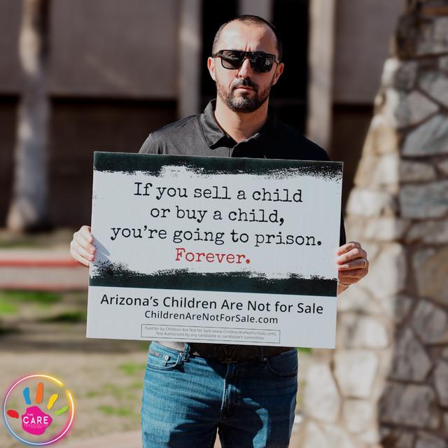A CARE advocate holding a sign that says Arizona's children are not for sale