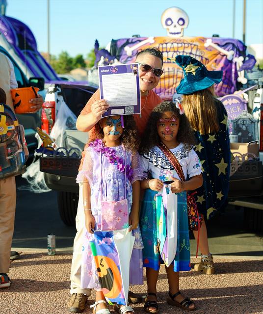 A CARE volunteer and two kids in costumes smiling at Trunk or Treat