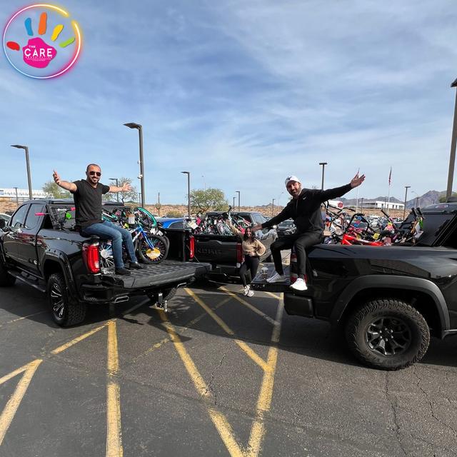 Two volunteers striking a pose on a pair of pickup trucks